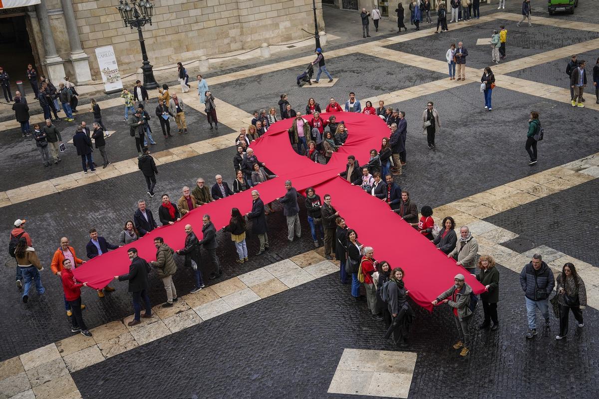 Despliegue de un lazo humano memorial del sida en la plaza de Sant Jaume de Barcelona.
