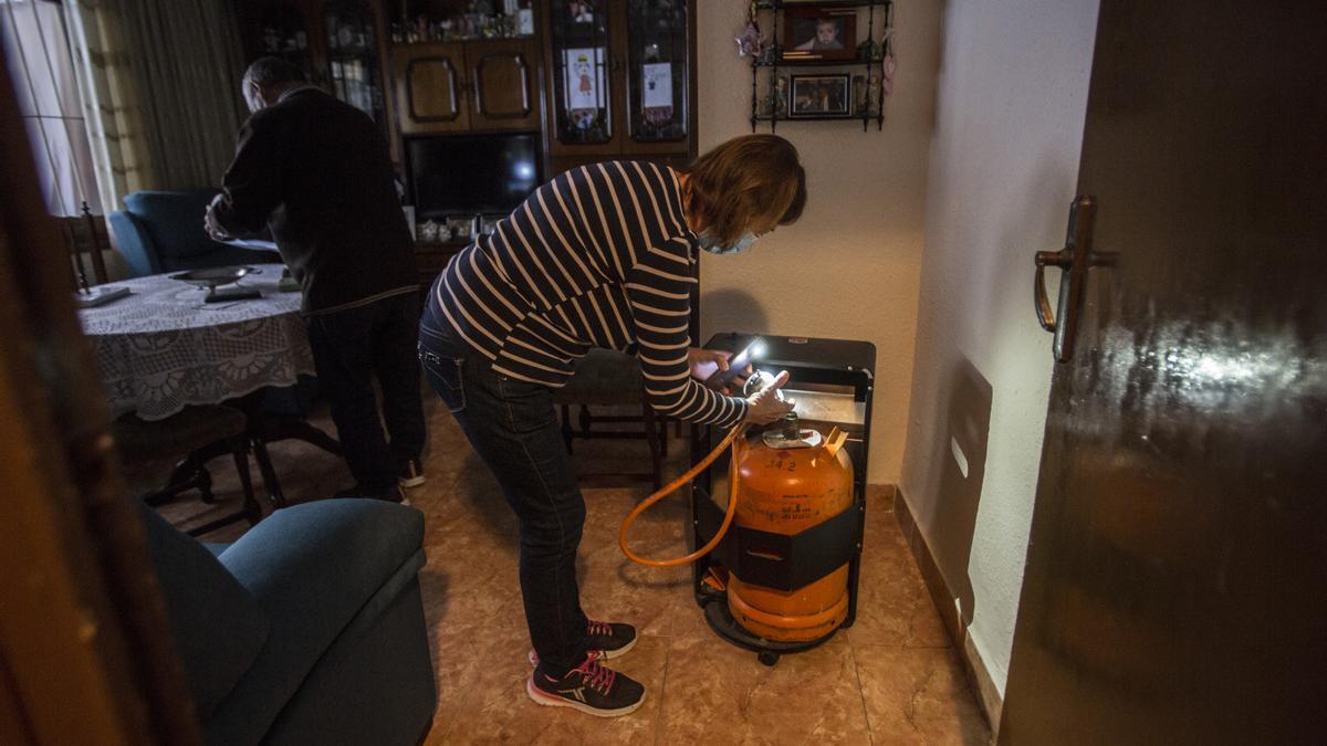 Una mujer coloca una botella de butano en su vivienda de Alicante.
