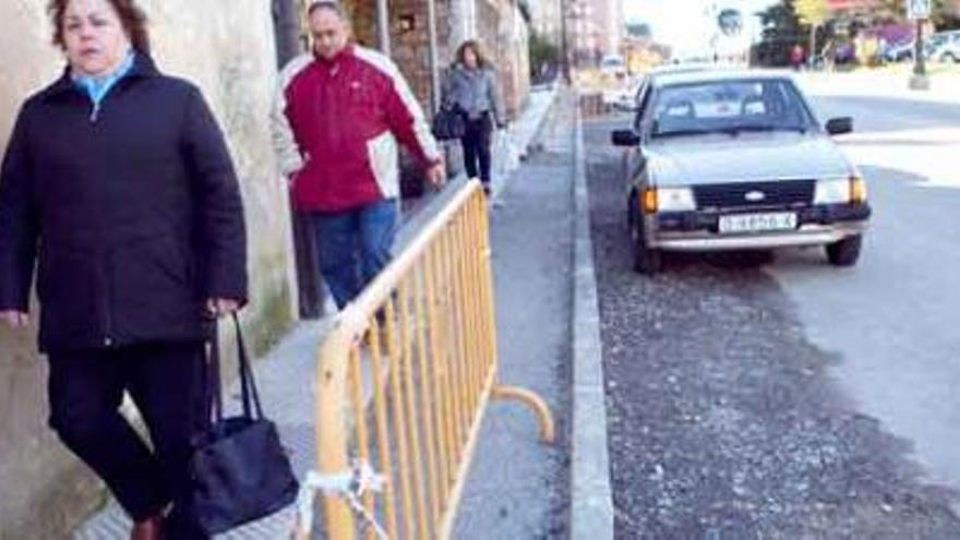 Varios peatones caminan por la nueva acera de La Corredoria, con la rotonda de Cuatro Caños al fondo.