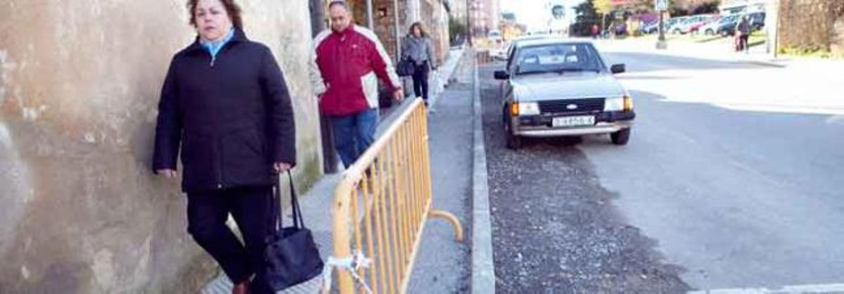 Varios peatones caminan por la nueva acera de La Corredoria, con la rotonda de Cuatro Caños al fondo.