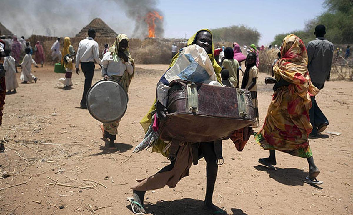 Un grup de persones fugen amb les seves pertinences del foc d’aquest dijous a la població de Kuma Garadayat, situada al nord de Darfur i controlada en el conflicte per la facció SLA - Free Will.