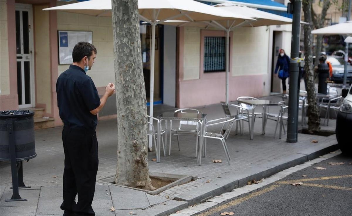 El mercado laboral pierde 137.500 empleos en mitad de la tercera ola. En la foto, un camarero observa la terraza de su restaurante, vacía, en un local de la rambla del Poblenou, en Barcelona. 