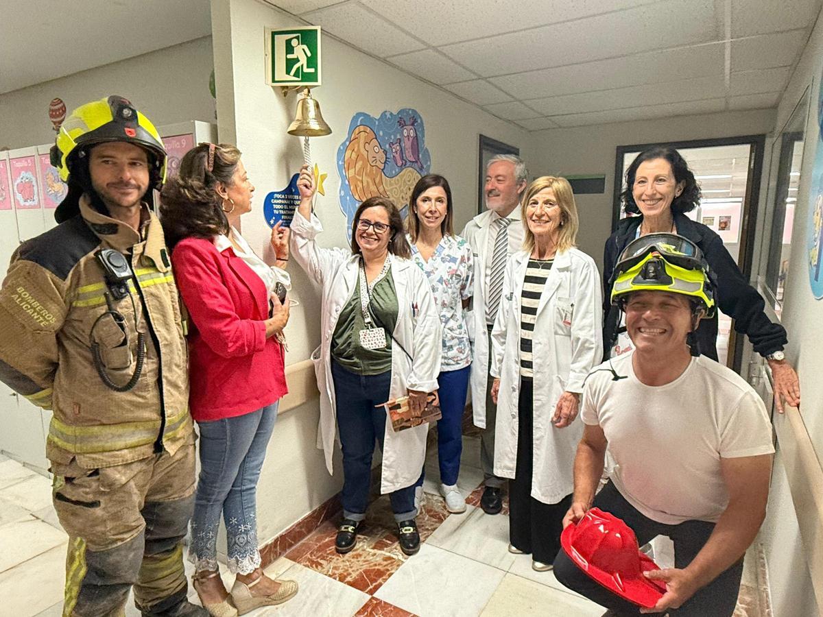 Médicos con la campana que se tocará cuando un niño reciba el alta en el Hospital de Alicante
