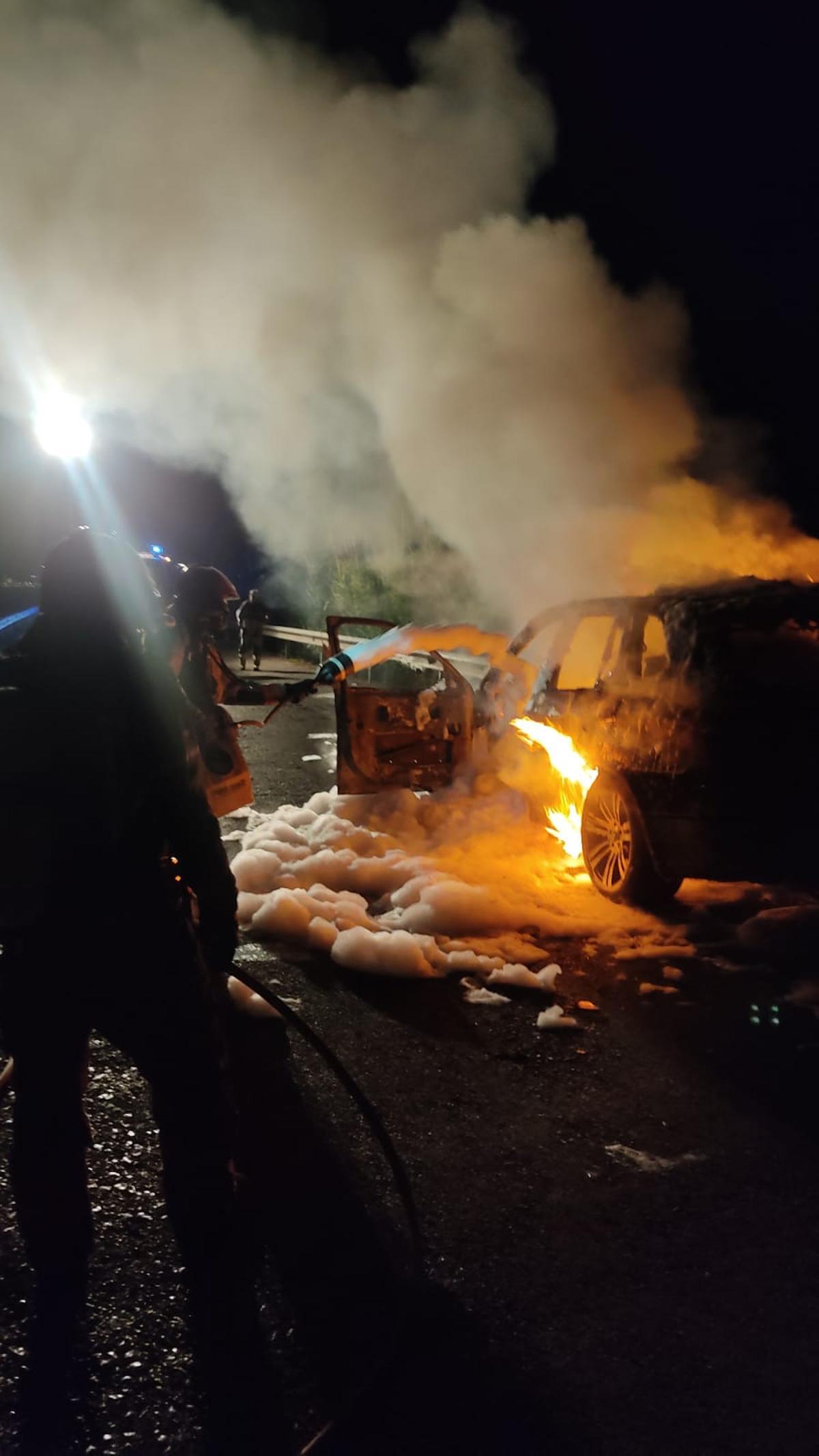 Imagen de los bomberos, atacando el fuego en el vehículo incendiado.