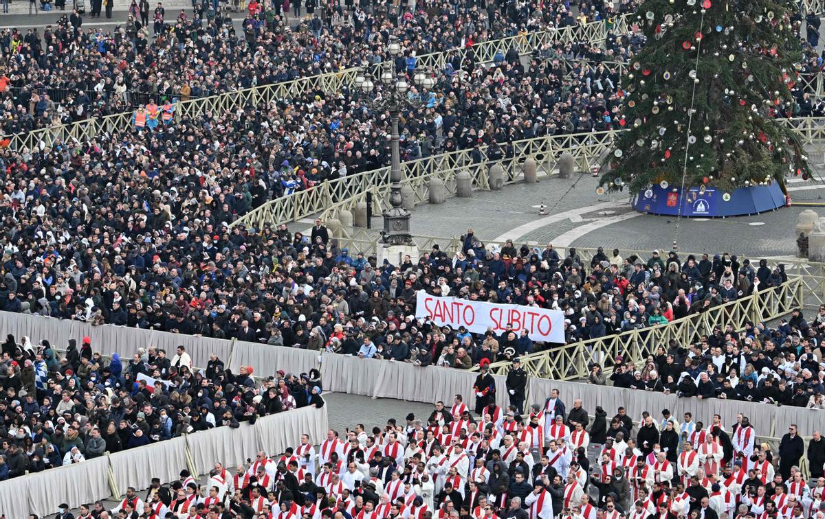 Fieles sostienen una pancarta que dice Santo subito, pidiendo la canonización inmediata del Papa emérito Benedicto XVI durante la misa fúnebre.