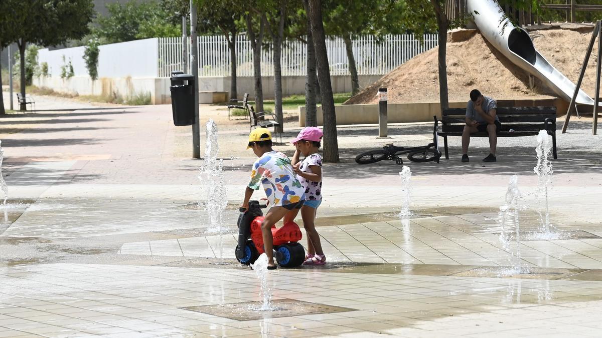 Unos niños se refrescan en un parque de Castelló.