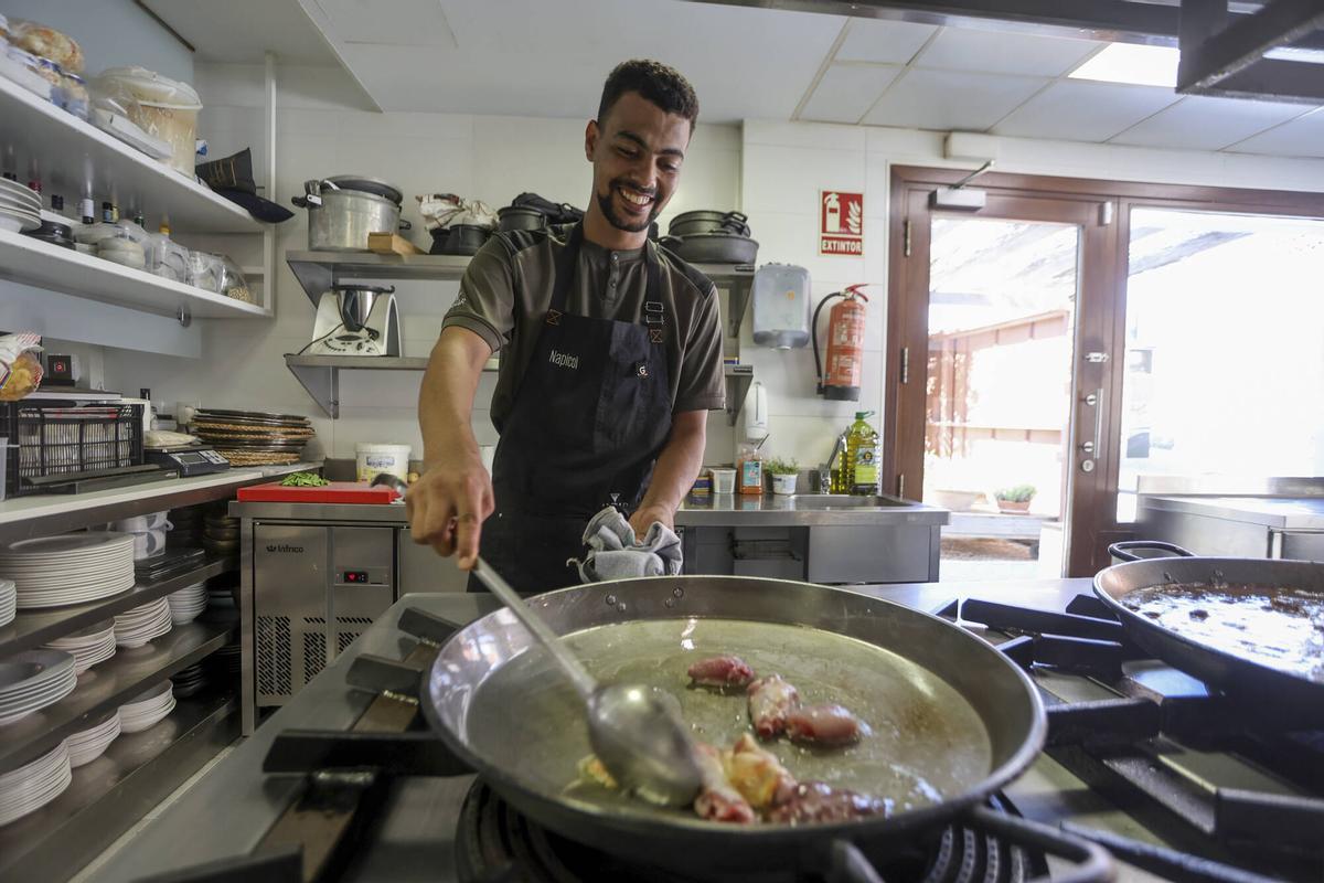 Un joven valenciano trabaja en un restaurante de la capital cocinando paellas.