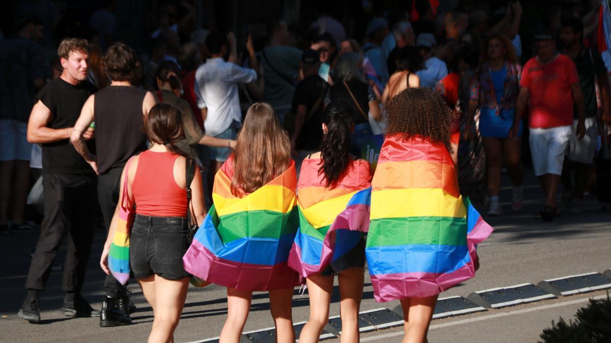 Quatre noies d&#039;esquenes amb la bandera LGTBI durant la rua del Pride de Barcelona