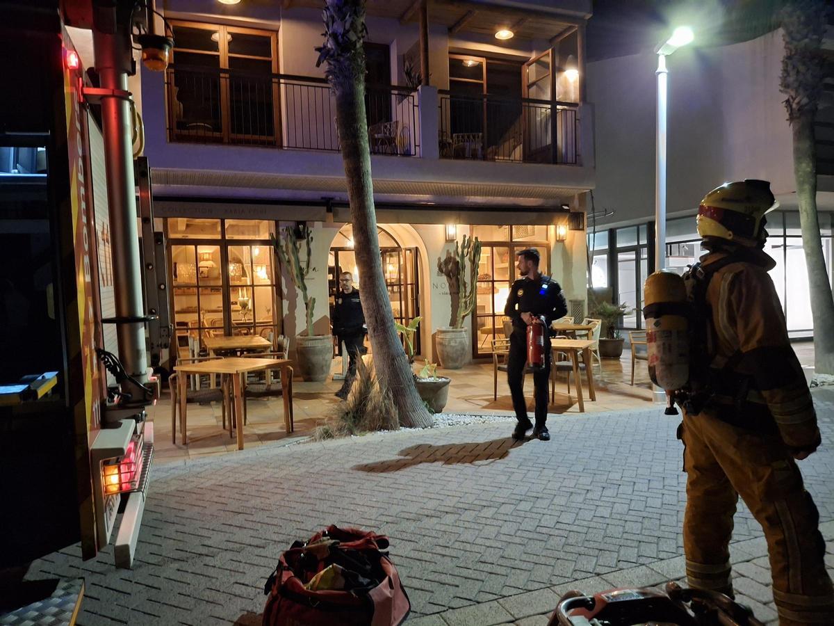 Dos policías locales salen del hotel portando los extintores que han utilizado para controlar las llamas