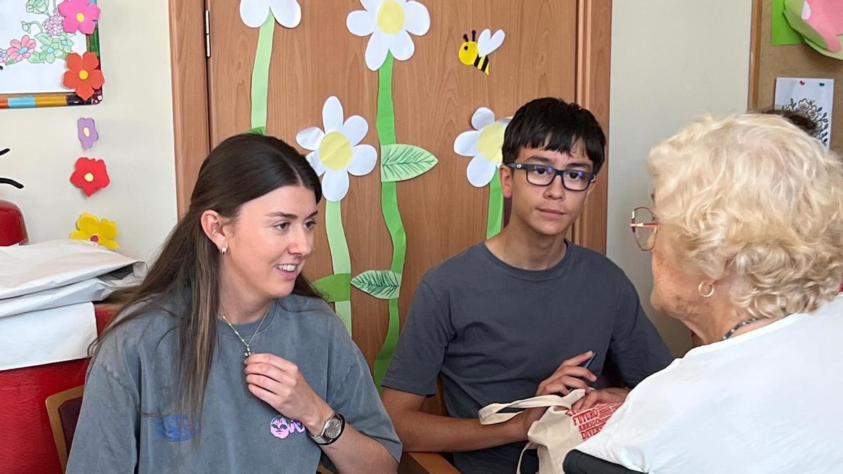 Dos jóvenes voluntarios de Cáritas Mérida Badajoz charlan con una usuaria de la residencia DomusVi.