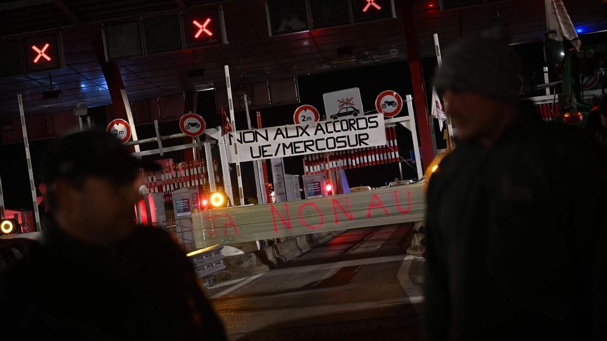 Manifestantes permanecen junto a una pancarta que dice “No a los acuerdos UE/Mercosur” durante una protesta de los sindicatos agrícolas franceses para denunciar los acuerdos entre la UE y Mercosur.