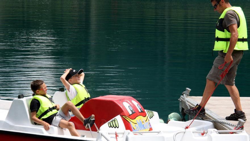 Pla de detall on es veuen dos nens i un monitor a punt de pujar a una barca del llac de la Molina.