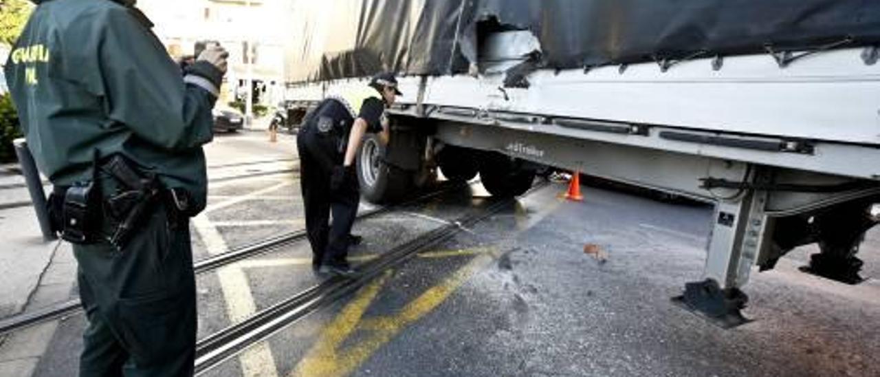 Agentes de la Policía Local y Guardia Civil observan el lateral del tráiler donde impactó el tranvía.