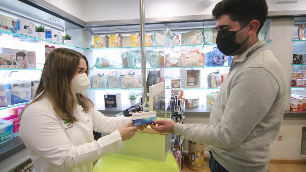 Una empleada de una farmacia de Córdoba dispensa una caja de Todacitan a un usuario.
