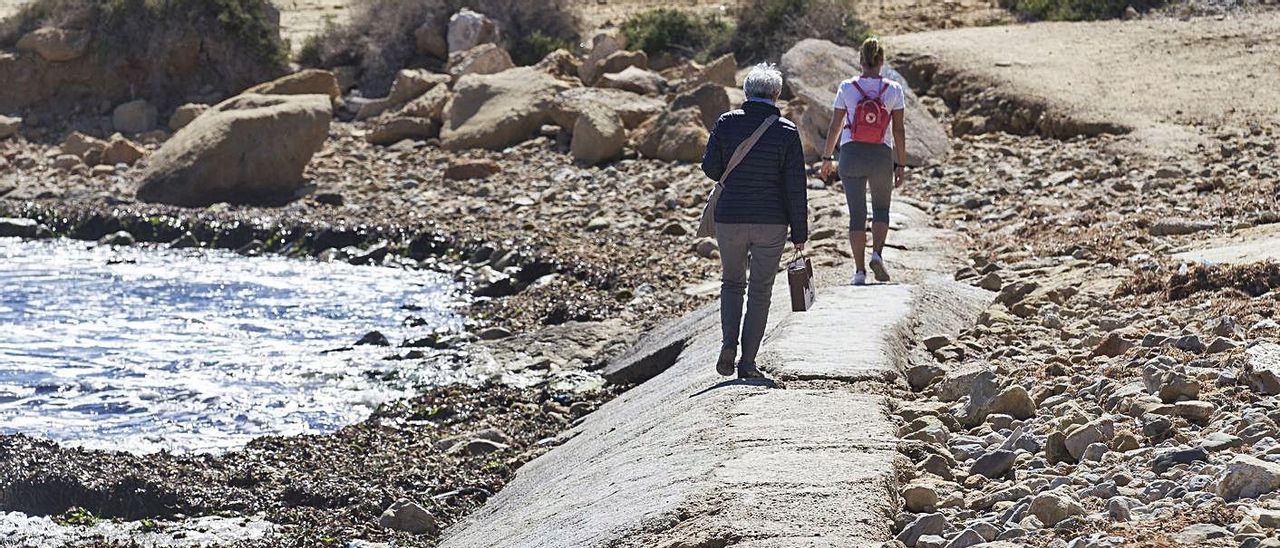 Usuarios de la playa de San Juan caminan por encima del colector hacia Cabo de las Huertas.
