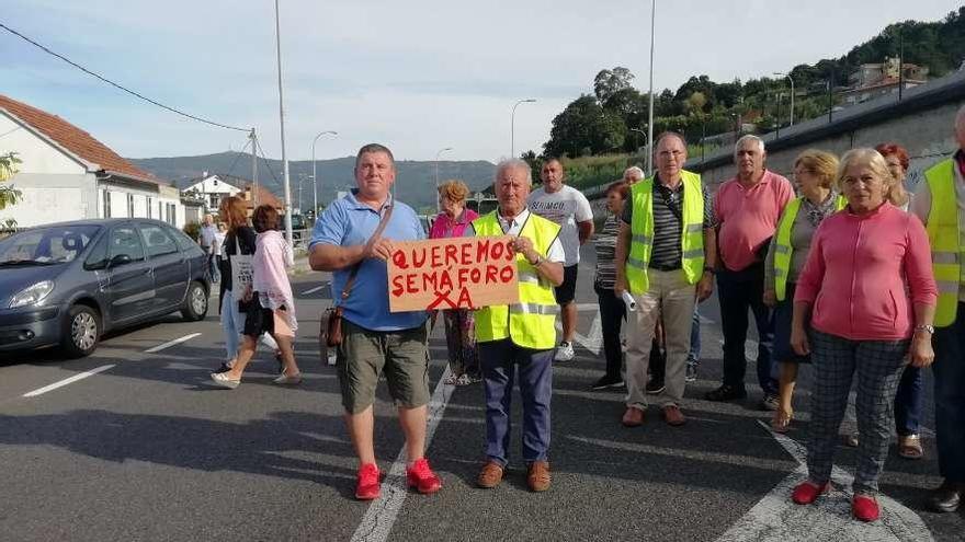 Un grupo de vecinos, ayer, concentrados en el cruce de la N-552 para exigir un semáforo. // FdV