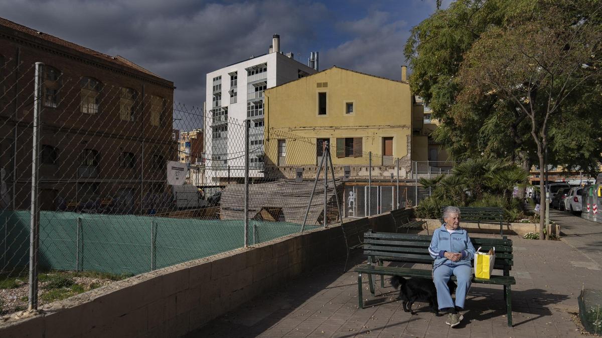 Una mujer sentada en un banco del jardín de Mossèn Amadeu Oller, junto a Can Batlló, en Barcelona.