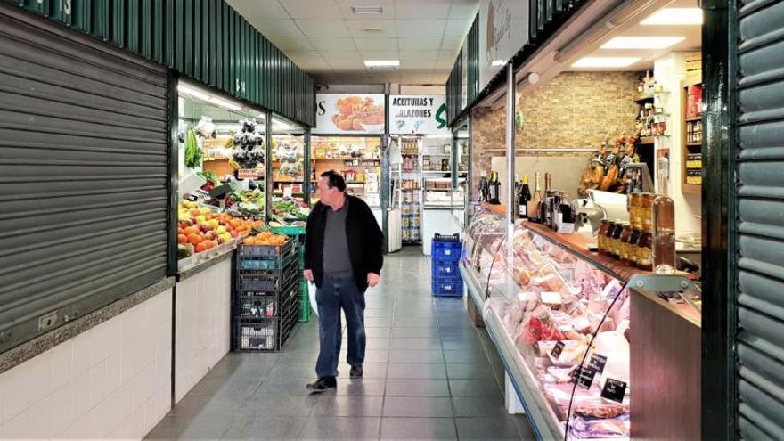 Varios vecinos comprando en el mercado de abastos de Crevillent, con negocios cerrados.