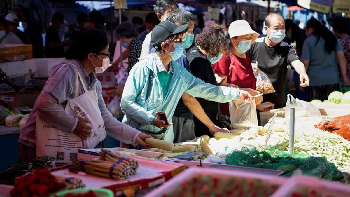 Varias personas compran en un mercado Cahowai de Pekín.