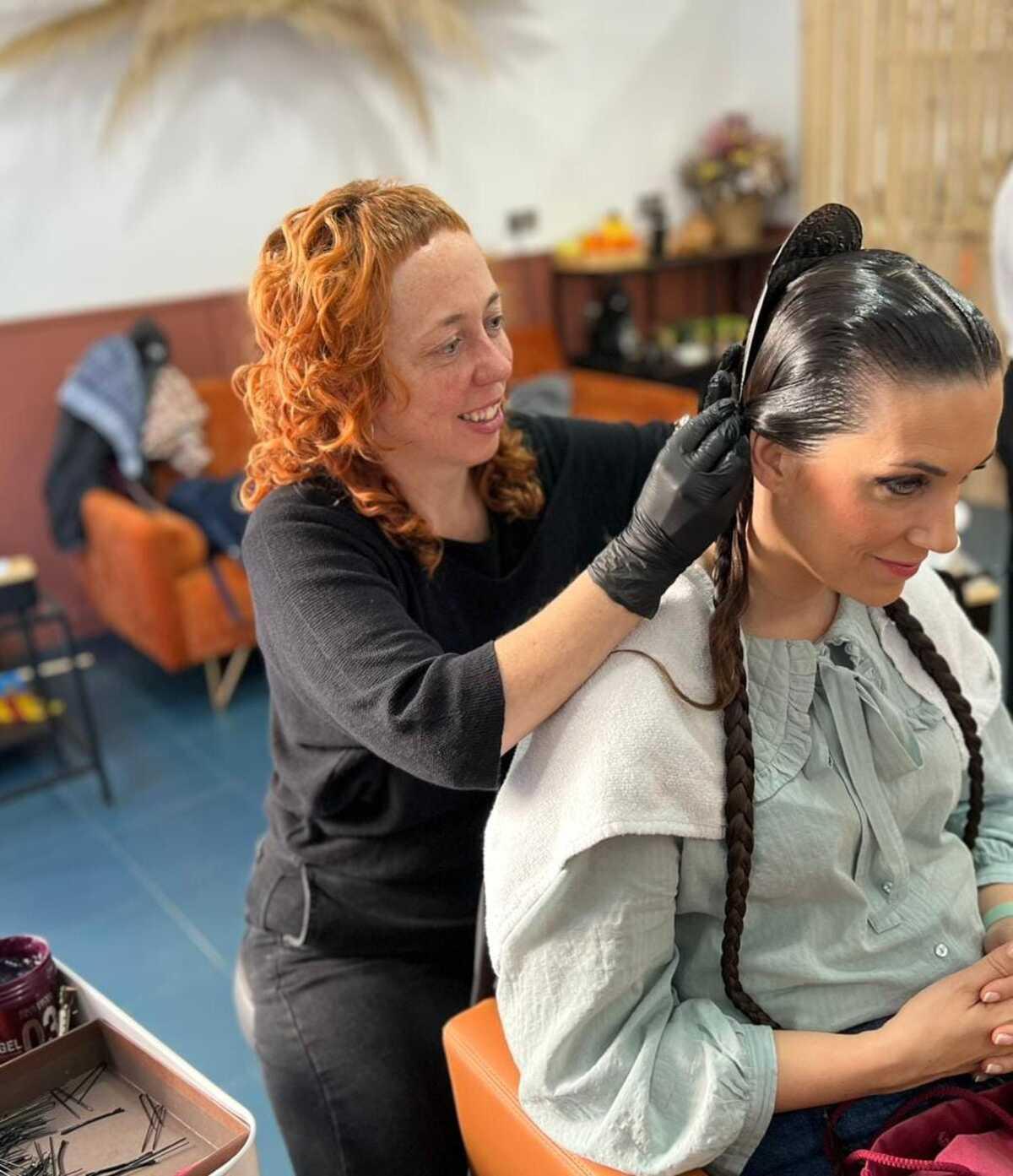 Ruth Peiró arregla el moño de una fallera en su peluquería de Benirredrà