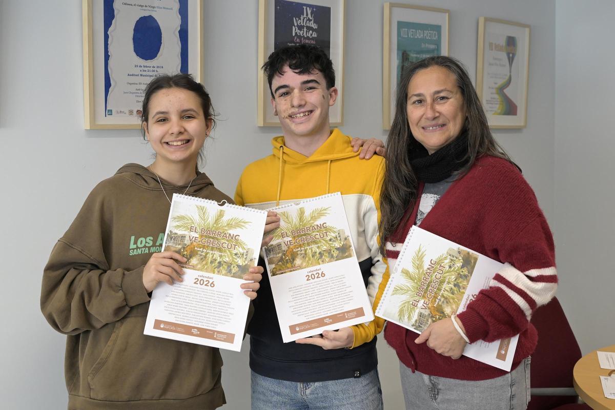 La concejala Olga Sandrós junto a dos estudiantes con el calendario.