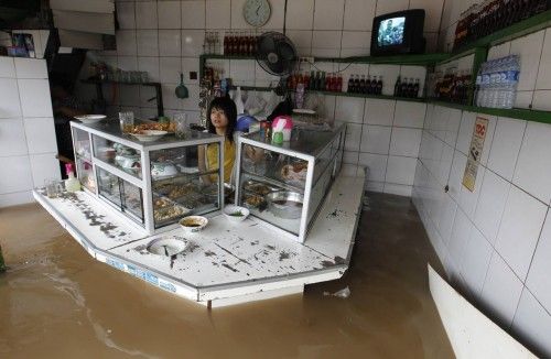 A woman stands in her food stall in the flooded business area in Jakarta