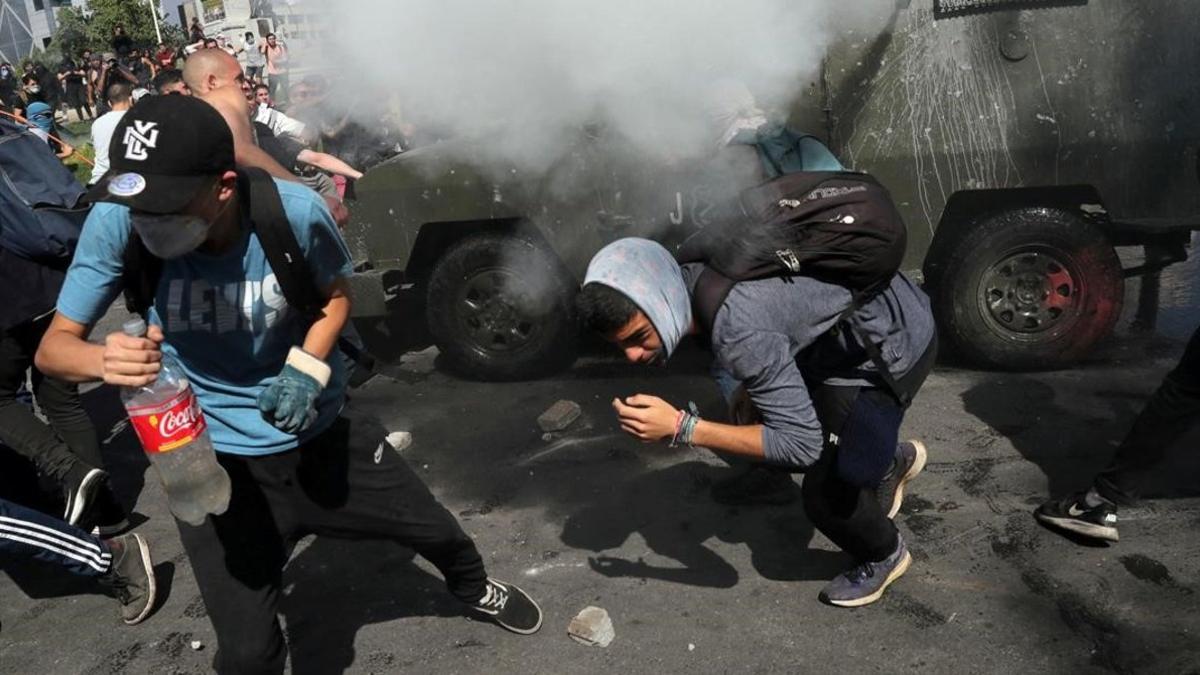 Manifestantes se refugian de los gases lacrimógenos en Santiago de Chile.