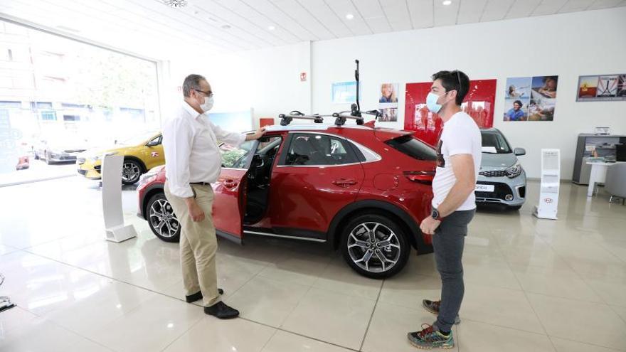 Un vendedor de automóviles enseña un vehículo a un cliente en un concesionario de la ciudad de Zaragoza. | ÁNGEL DE CASTRO