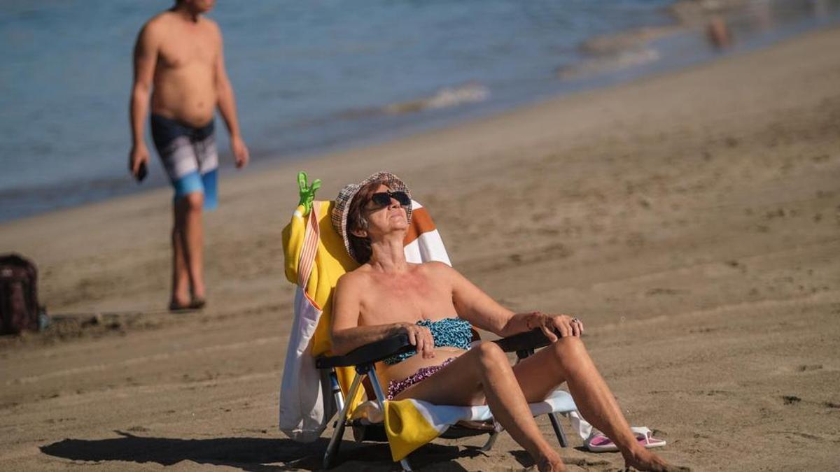 Una turista toma el sol sentada en su hamaca en una playa del sur de Tenerife.