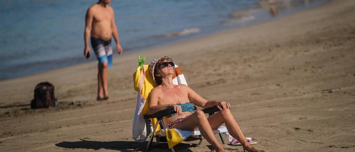 Una turista toma el sol sentada en su hamaca en una playa del sur de Tenerife.