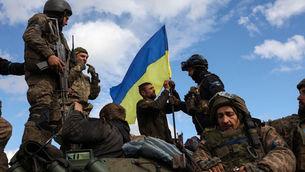 Soldados ucranianos colocan una bandera de su país en un vehículo armado cerca de Lyman, en la región de Donetsk