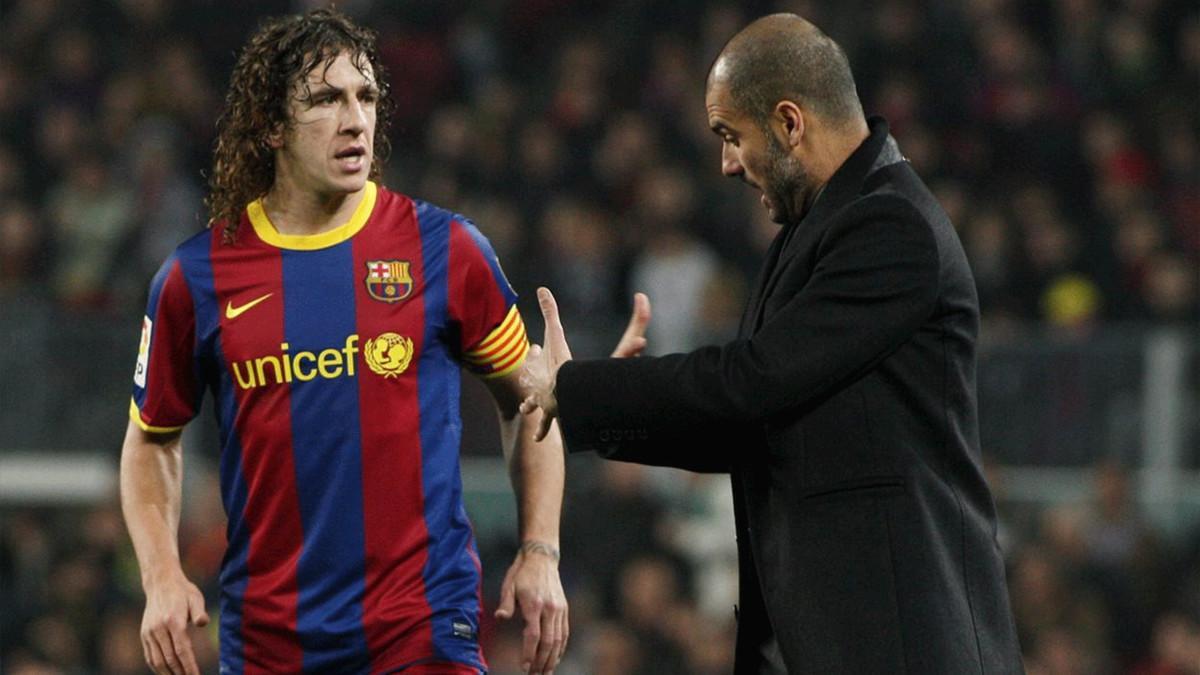 Puyol escucha las intrucciones de Josep Guardiola desde la banda durante el Barça-Málaga de la temporada 2010/11