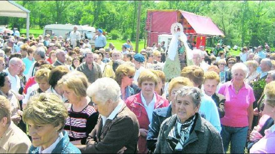 Varias mujeres acarrean la imagen de la Virgen de la Cabeza, rodeadas de gente, durante la procesión en el santuario de Meres.