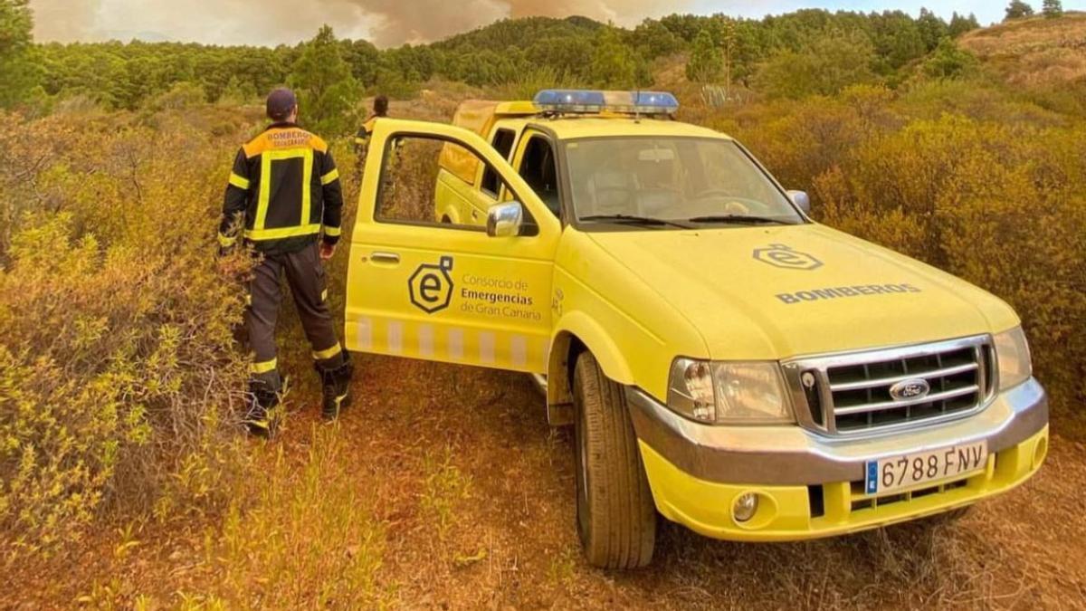 Dos bomberos del Consorcio de Emergencias de Gran Canaria vigilan un incendio forestal.