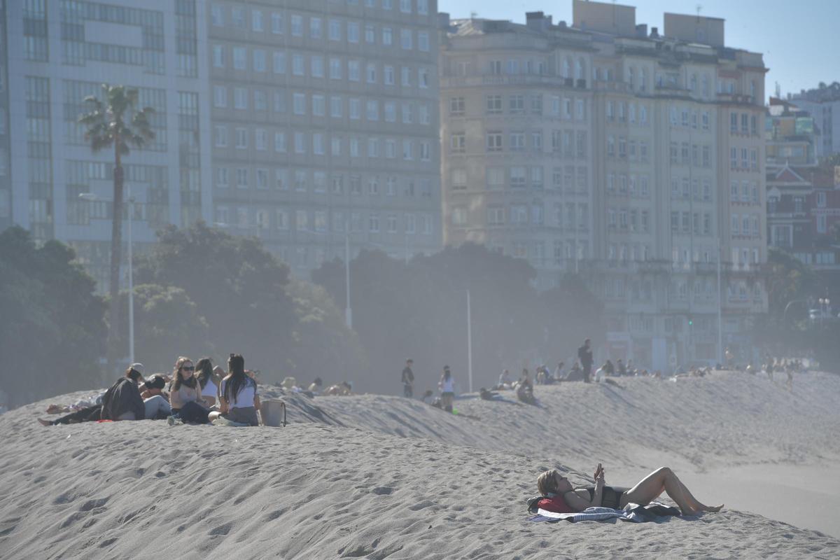 Gente disfrutando del buen tiempo esta semana en la playa de Riazor