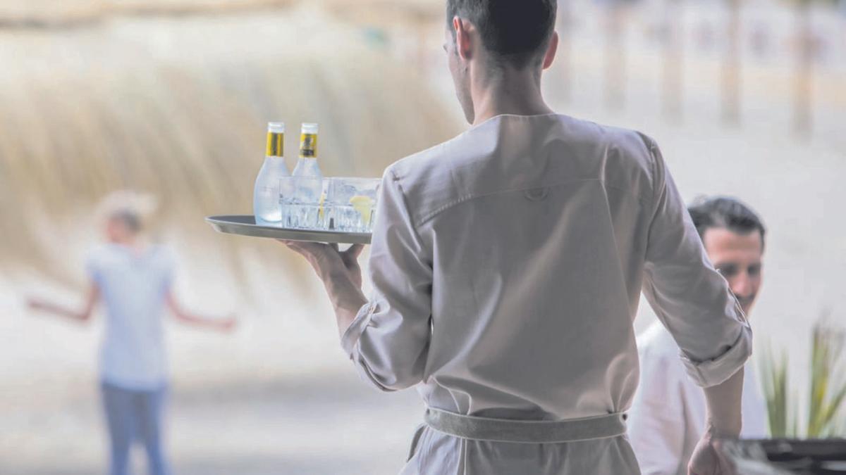 Ein Kellner trägt Getränke auf eine Terrasse. | FOTO: B. RAMÓN