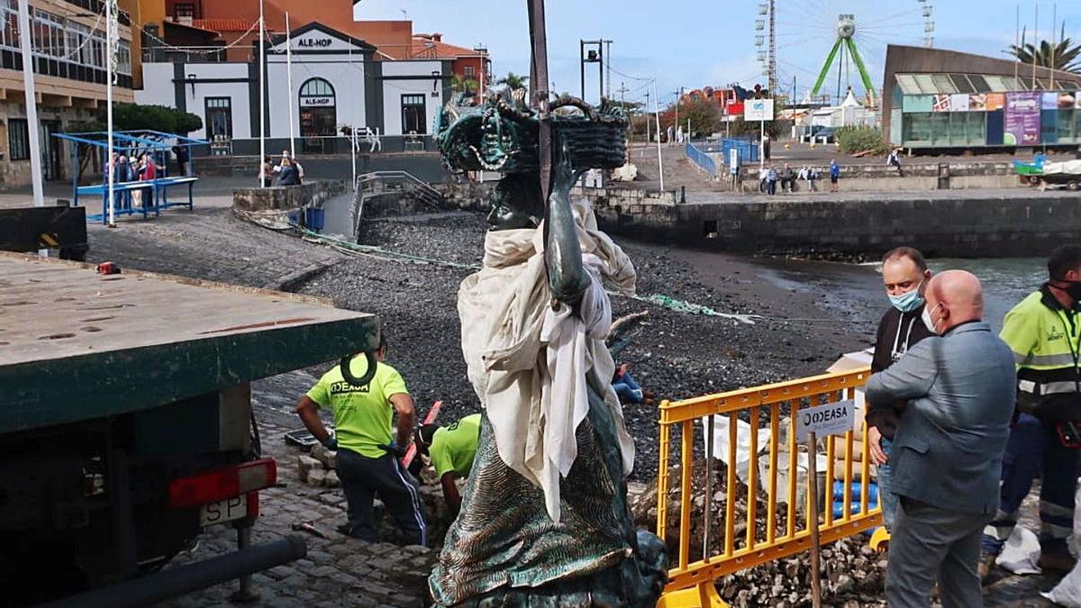 La escultura se ha sometido durante semanas a una laboriosa reparación y restauración antes de regresar ayer al muelle portuense. El artista Julio Nieto (abajo a la izquierda) y Miguel Ángel Padilla, de la fundición Fornax, en La Matanza de Acentejo, se encargaron de los trabajos. | e.d.