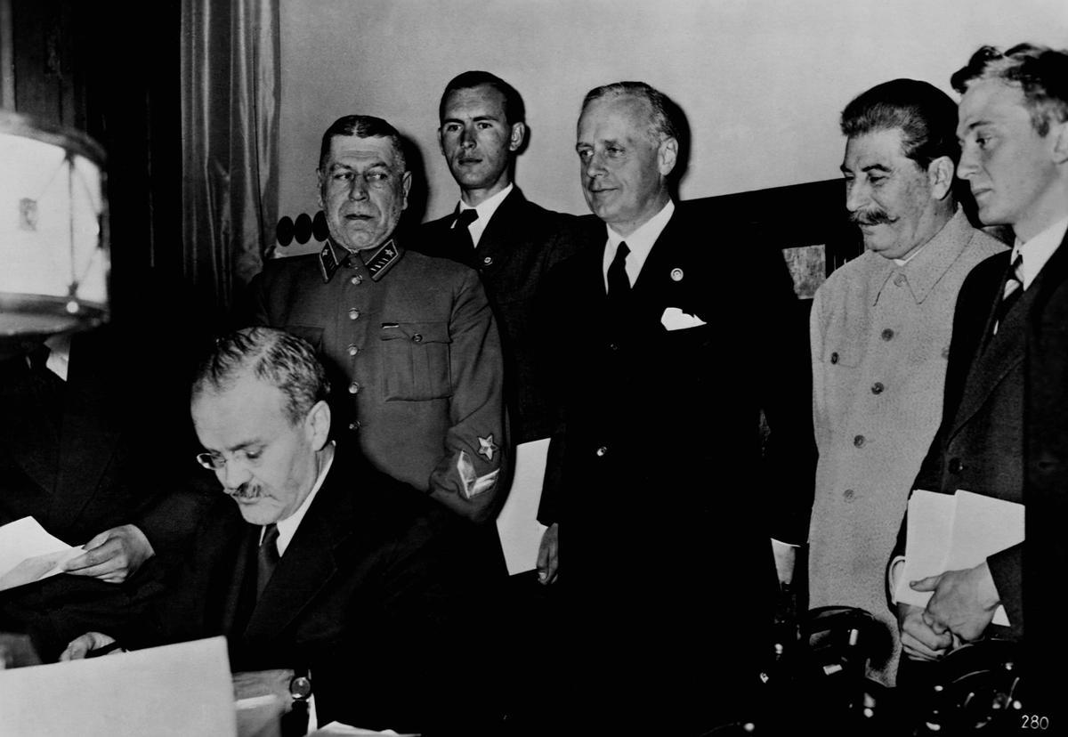 Viacheslav Mólotov, ministro de Relaciones Exteriores de la URSS, firma en 1939 el pacto de no agresión nazi-soviético con su homólogo alemán Joachim Ribentropp (detrás de él y a la dcha. de Stalin).