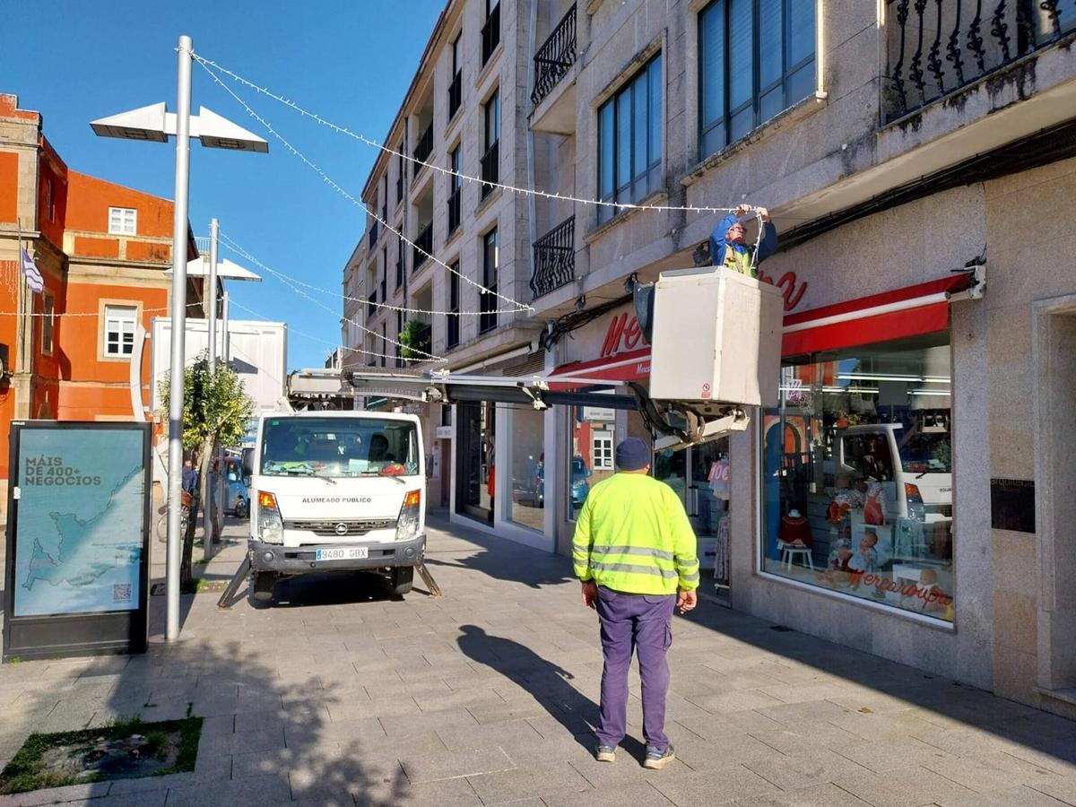 La brigada municipal, ayer, colocando el alumbrado navideño en la calle Eduardo Vincenti de Bueu.