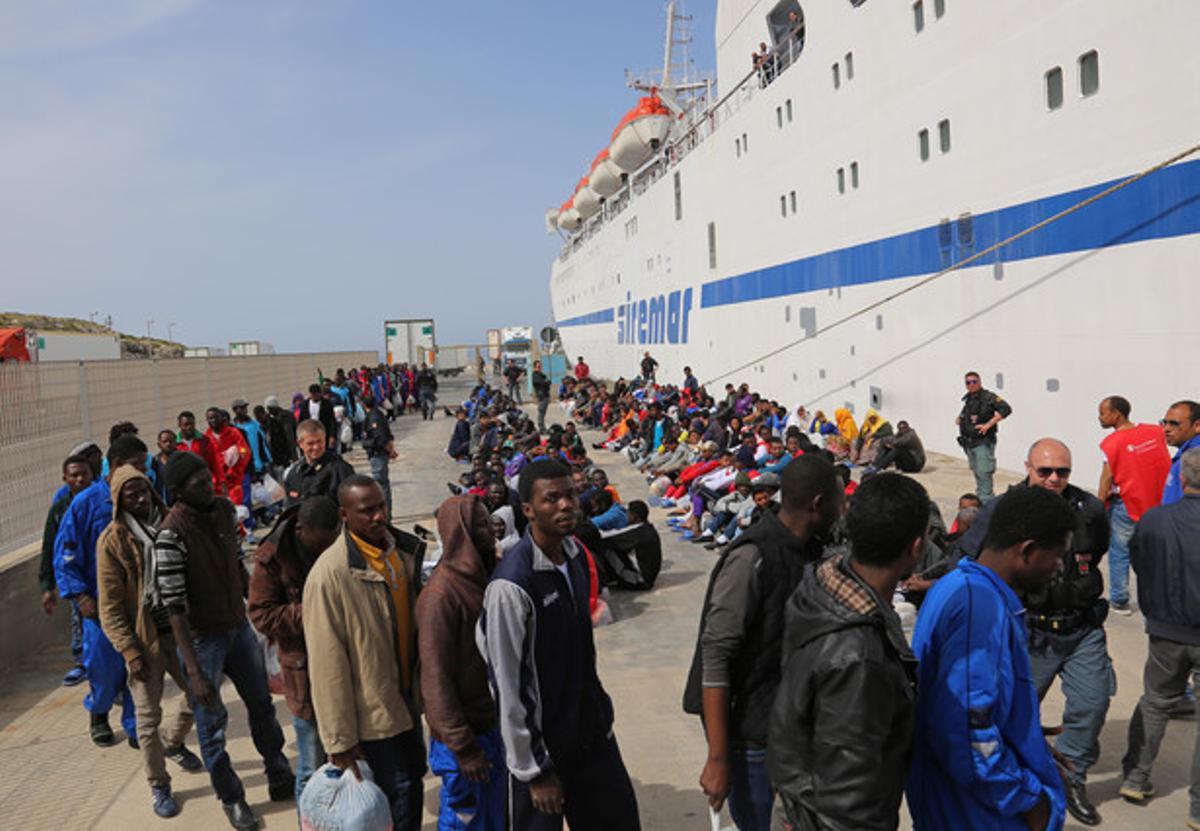 Un grup d’immigrants esperen per embarcar en un vaixell que surt de l’illa de Lampedusa.