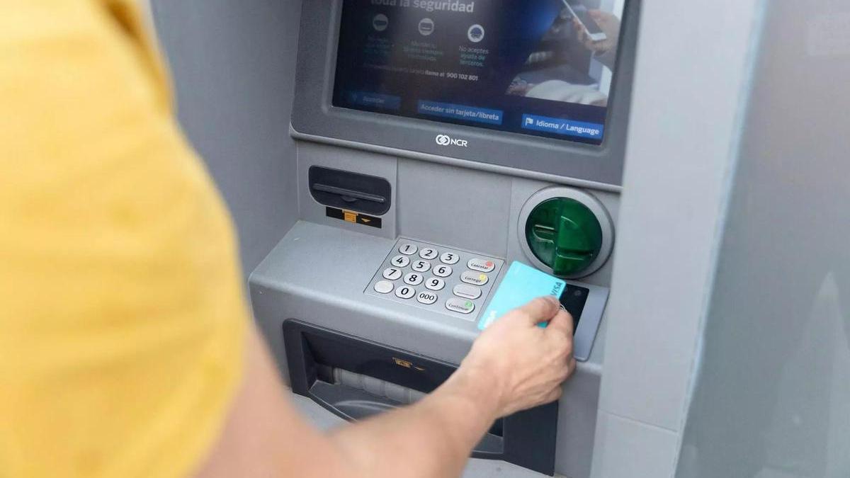 Una persona saca dinero del cajero.