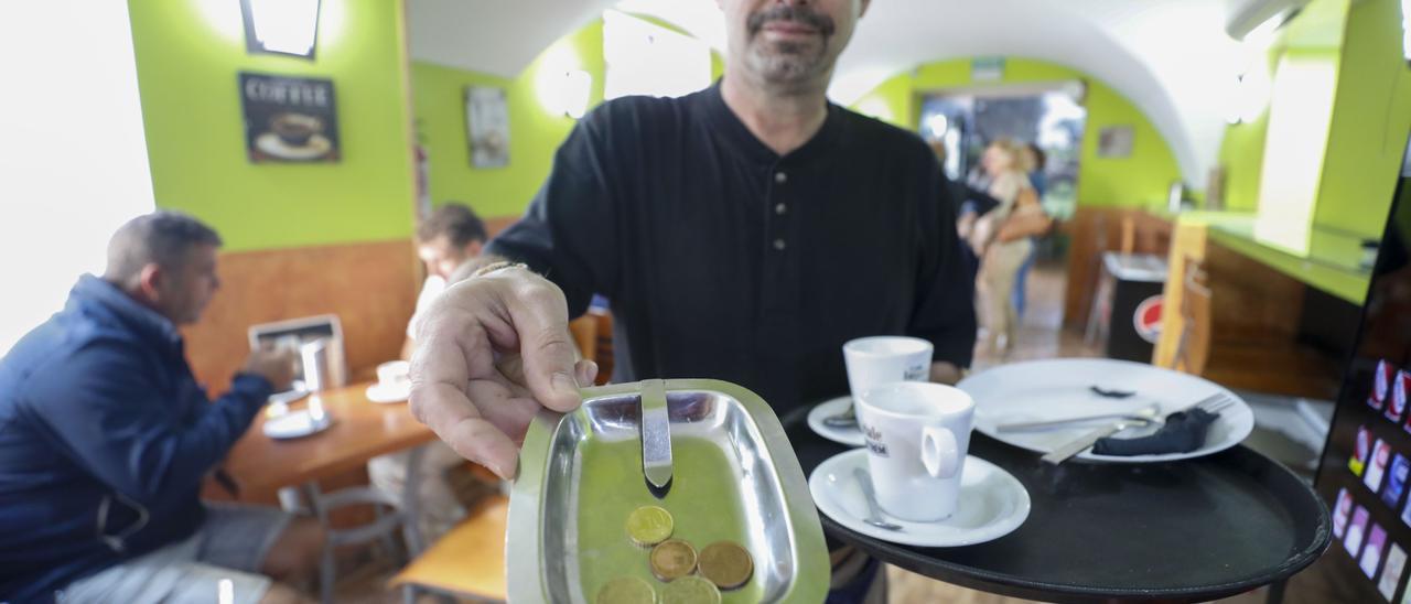 Un trabajador de ‘Los Ibéricos’, un establecimiento de Cáceres, retira una mesa y el plato de  propina.