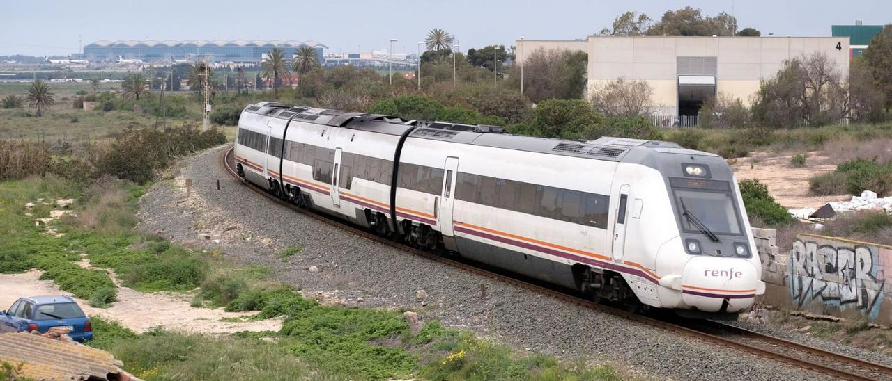 Una imagen del tren de Cercanías, circulando entre Elche y Alicante, con el aeropuerto al fondo. | AXEL ÁLVAREZ