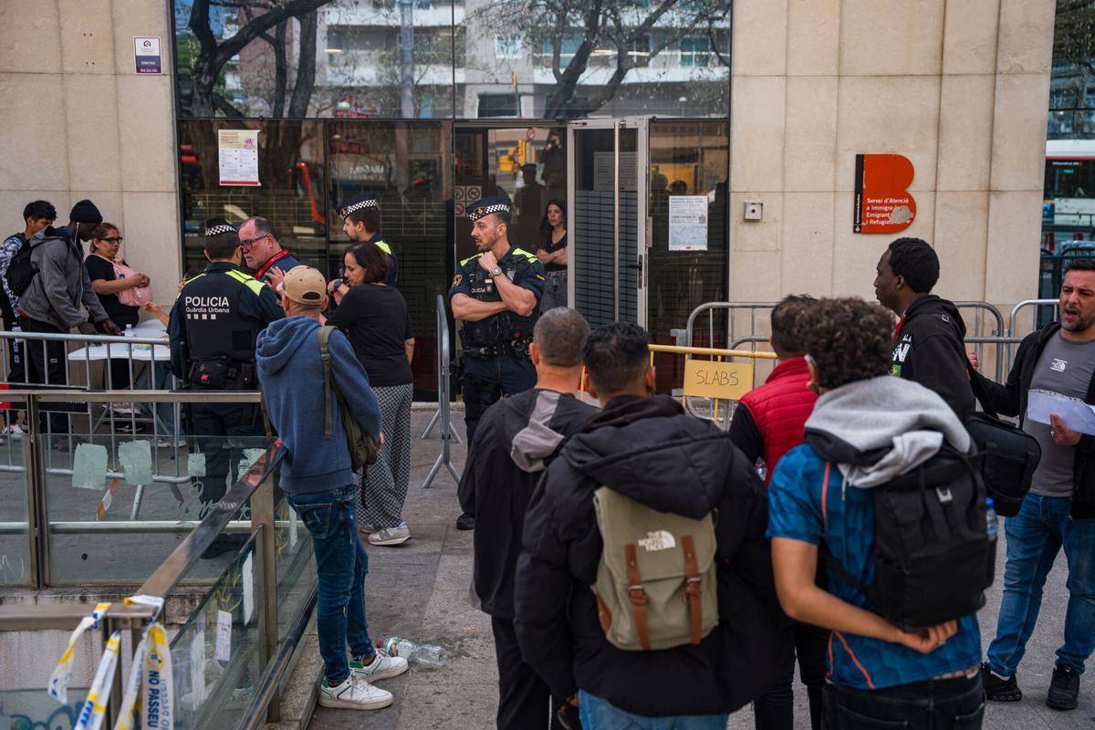 Caos y una larga cola de personas que esperan regularizar su situación en España en la Oficina de Benestar Social i Família de Barcelona-Sants/Eixample.