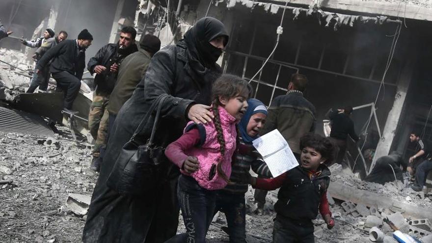 Una mujer siria y sus hijos tras un bombardeo.
