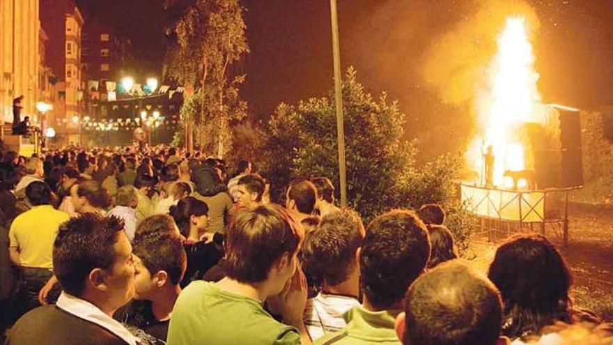 Asistentes a las fiestas de San Juan de La Llera, con la foguera al fondo, el año pasado.