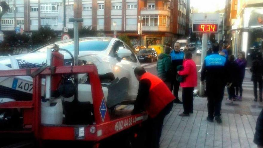 El vehículo, subido en la grúa, con el poste contra el que chocó al fondo a la derecha.