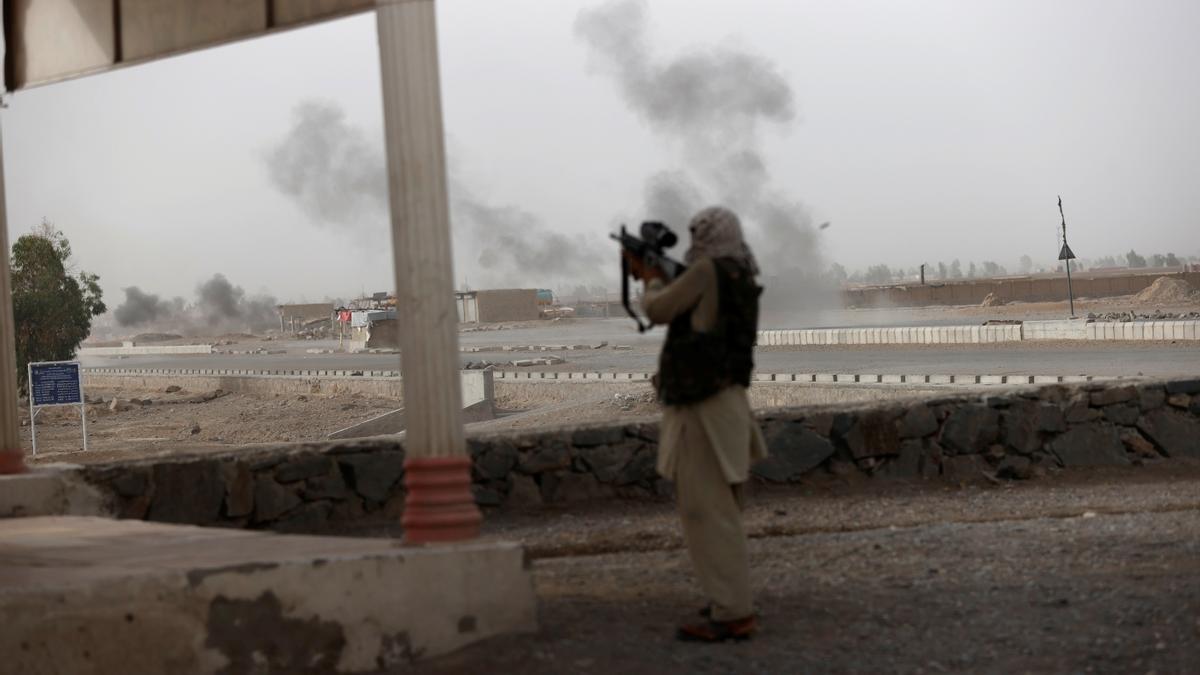 An Afghan soldier holds a gun and looks towards Taliban positions as smoke rises in the distance from clashes on the outskirts of Spin Boldak in Kandahar province, Afghanistan