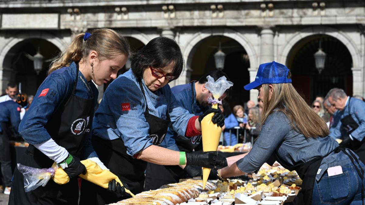 Reparto de la Corona de la Almudena gigante en la Plaza Mayor, organizado por ACYRE Madrid, en colaboración con el Ayuntamiento, este domingo.