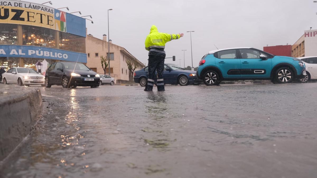 Un agente de la Policía Local, con el agua por los tobillos, dirigiendo el tráfico esta tarde en la avenida del Mediterráneo.